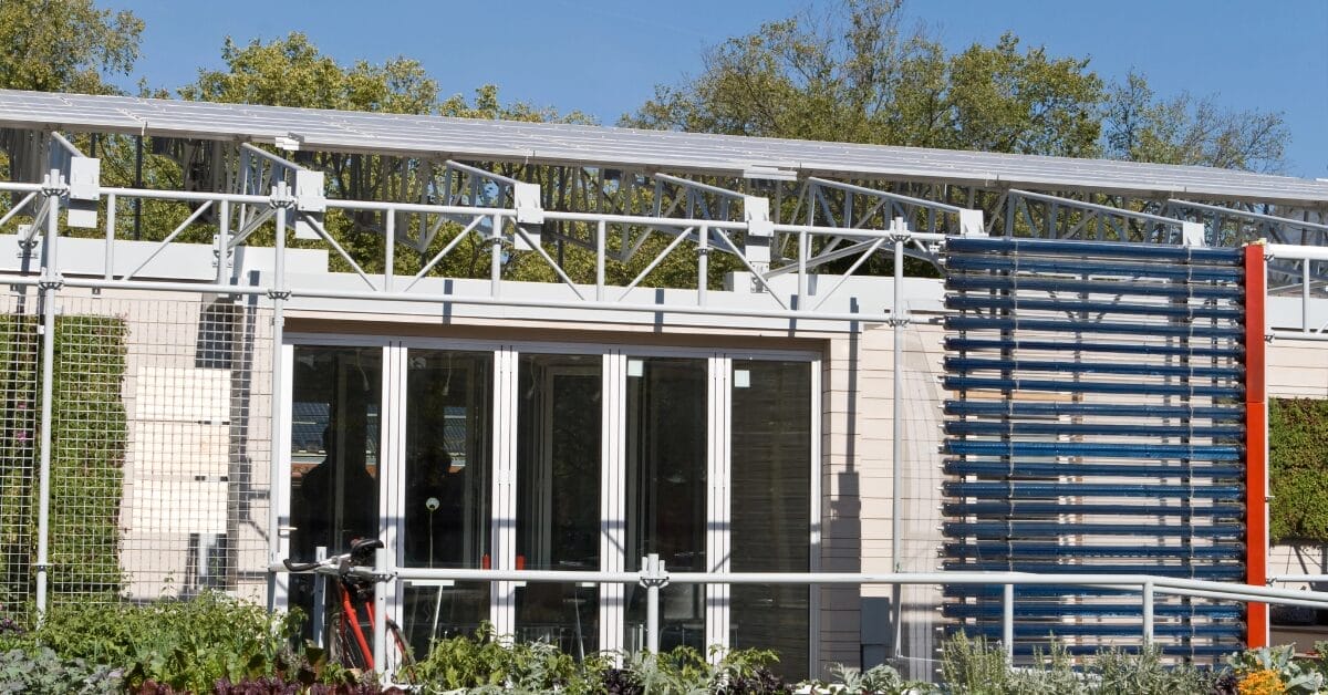 Exterior of a modern solar home with PV panels on the roof and a solar hot water heater on the far right.