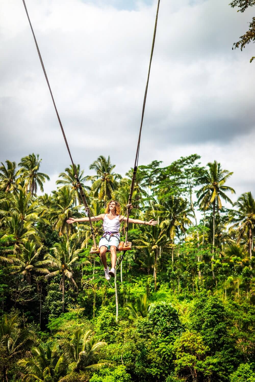 A woman joyfully swinging on ropes in a charming treehouse.