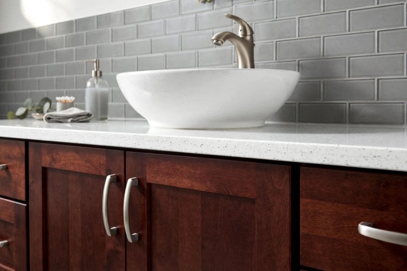 gray and white bathroom with cherry cabinets: compact single vanity with drawers beneath a white basin