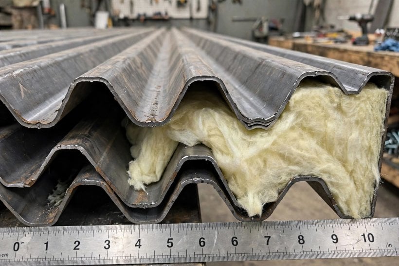container rain simulator: corrugated container wall cross-section with fiberglass batt held against it, showing the air gaps in the valleys