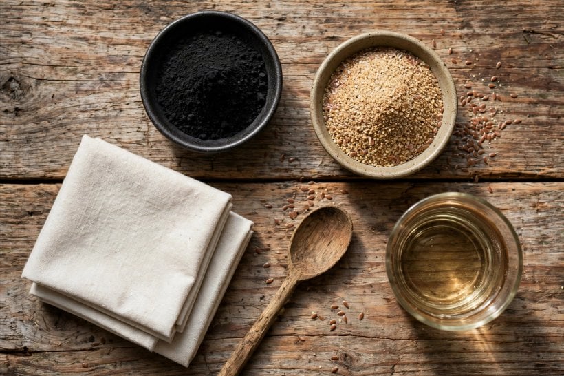 how to make a charcoal poultice: ingredients laid out ready — charcoal powder, ground flaxseed, cloth and warm water