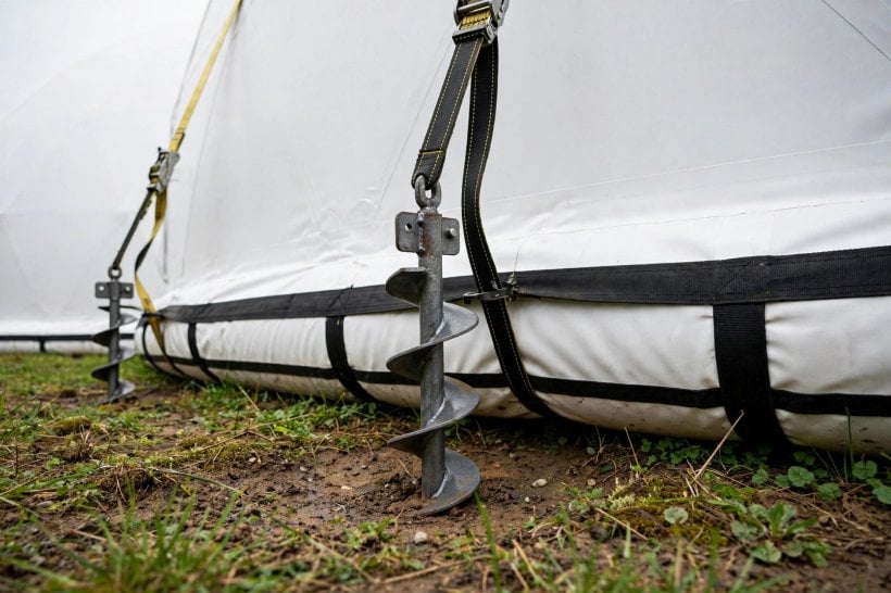 Inflatable House Structural Engineering: auger ground anchors and straps securing a membrane base beam