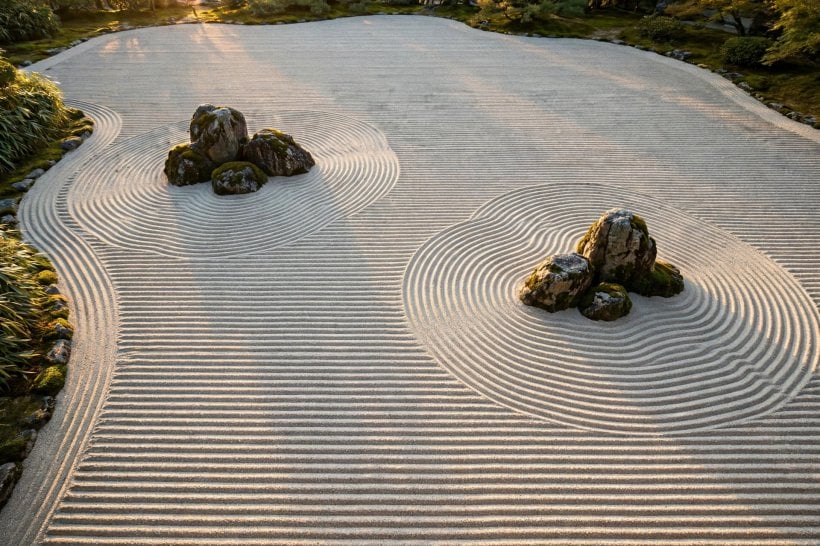 Japanese zen rock garden: concentric wave arcs raked around rock groups in pale gravel