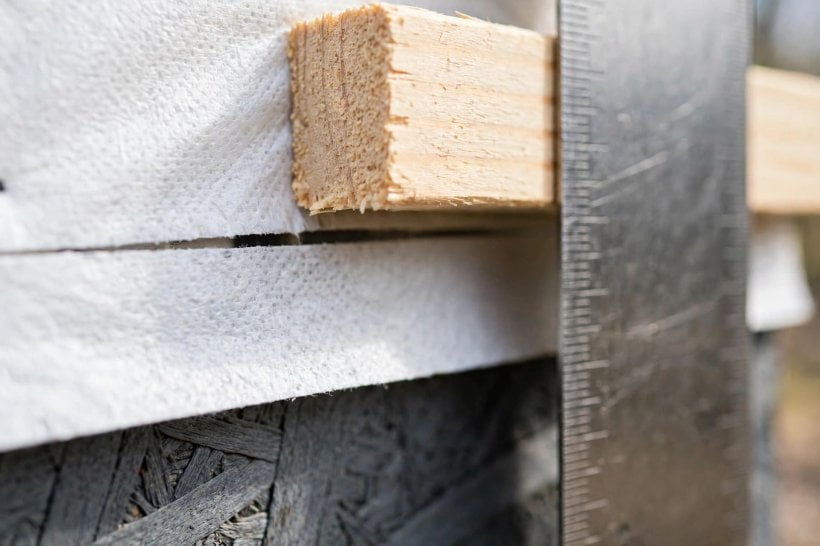 rain screen installation: measuring a three-quarter-inch furring strip against house wrap