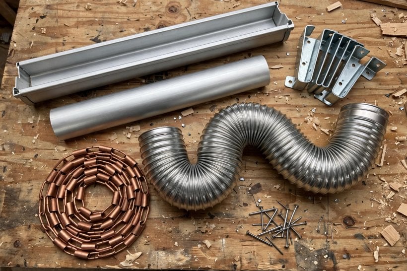 removable gutter systems: gutter sections, cradle brackets, flexible downspout and rain chain parts laid out on a workbench