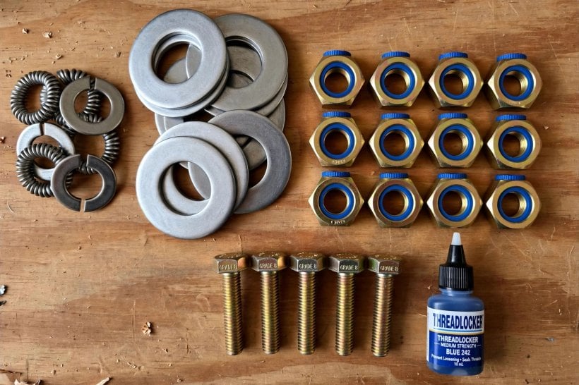 how to secure a tiny house to a trailer frame: flat washers, lock washers, nyloc lock nuts and thread locker laid out on a workbench