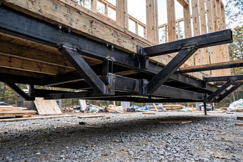how to secure a tiny house to a trailer frame: steel outriggers welded to the trailer frame carrying the wall load