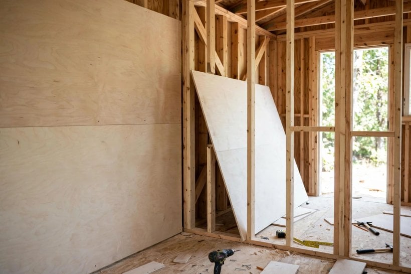 sheathing weight calculator: pale plywood wall panels being fitted inside a tiny house frame